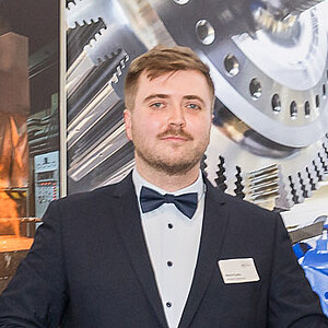 Marcel Kupke steht bei der Preisverleihung auf der Bühne und hält seinen symbolischen Scheck über 700 Euro.
