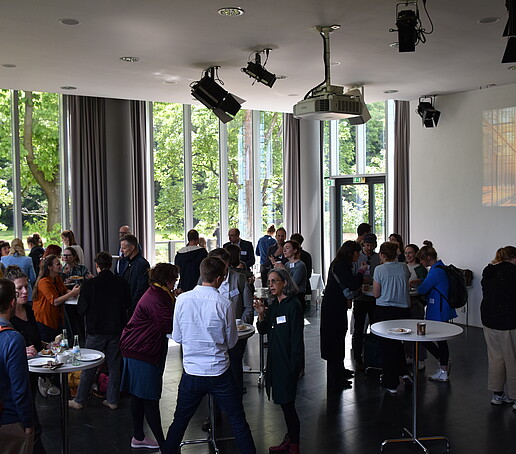 [Translate to Englisch:] Große Grauppe an Stehtischen in der Aula