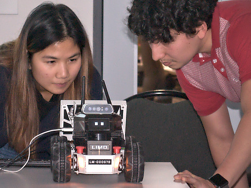 Eine thailändische Studentin und ein Student demonstrieren die autonomen Funktionen eines Modellfahrzeugs.
