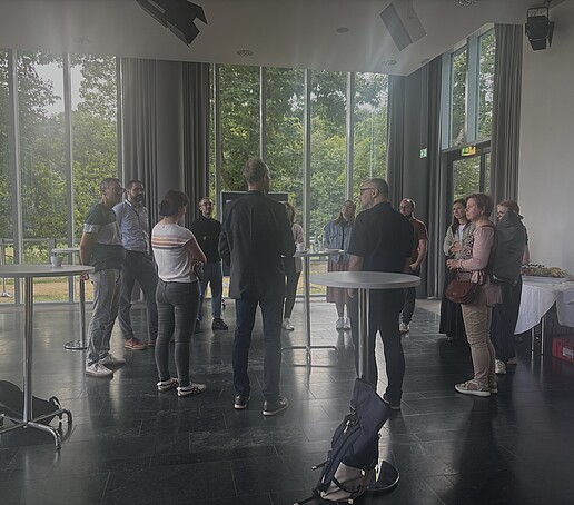 [Translate to Englisch:] Tagungsteilnehmer stehen in der Pause um Stehtische