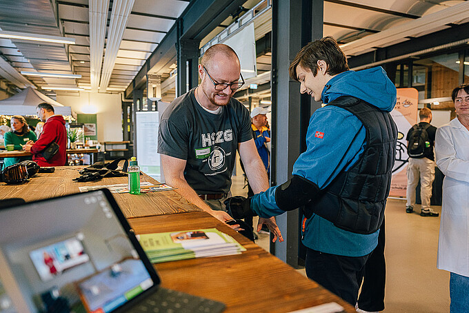 An employee helps a visitor put on the age simulation suit. 