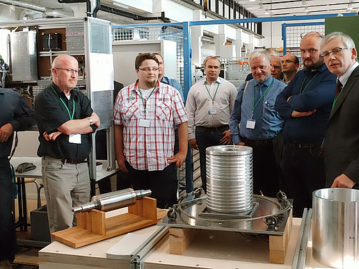 Prof. Ralf Werner (TU Chemnitz, 2nd from right) explaining experimental equipment during the lab tour