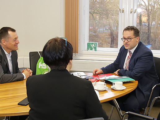 Bundestagsabgeordneter Herbst, Frau Schütz und der Rektor sitzen am Tisch bei einer Besprechung.