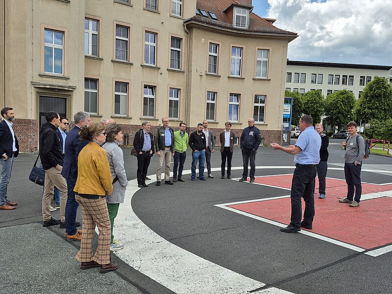 Eine Gruppe Menschen steht rund um den Helikopterlandeplatz vor dem Klinikum Zittau.