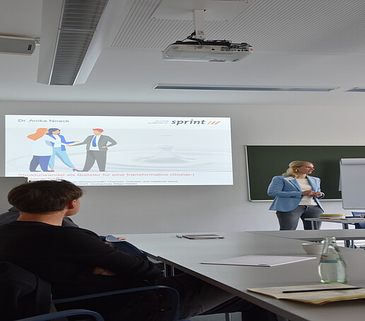 [Translate to Englisch:] Rednerin vor Projektionswand