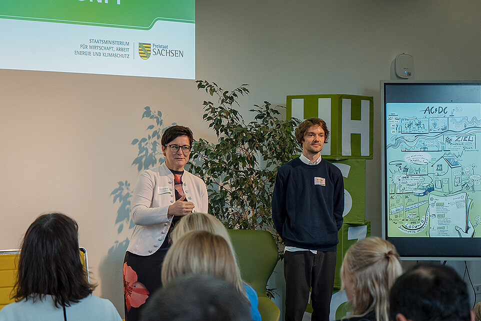 Zwei futureSAX-Mitarbeiter sprechen in der Aula vor Publikum.