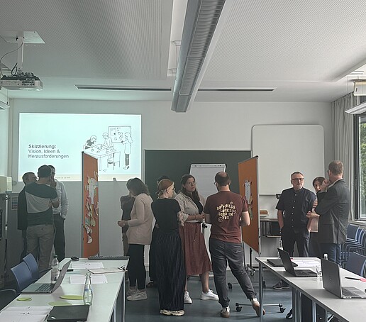 [Translate to Englisch:] Teilnehmer stehen um Pinnwände und tauschen sich aus