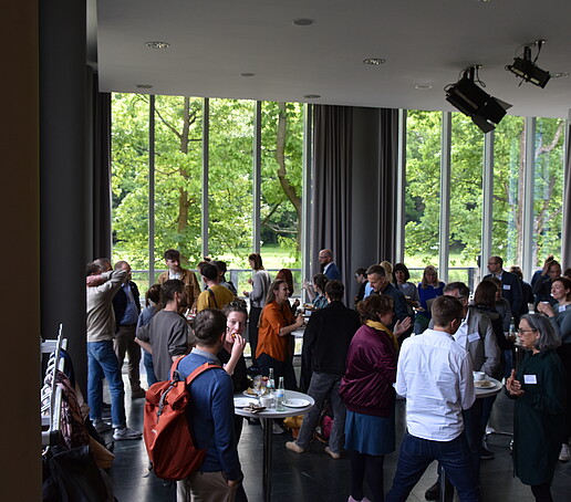 [Translate to Englisch:] Große Gruppe an Stehtischen in der Aula