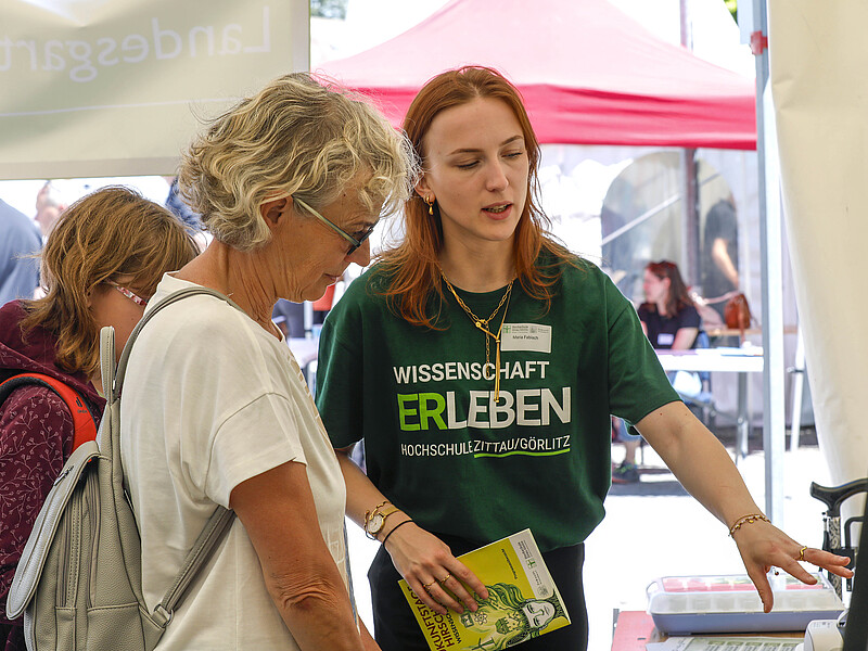 [Translate to Englisch:] Besucherin lässt sich die Technik erklären