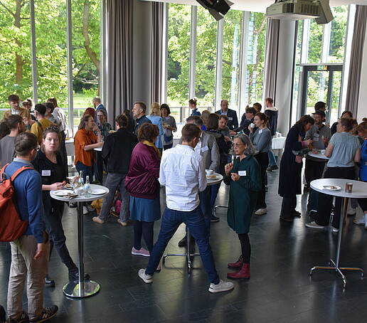 [Translate to Englisch:] Große Gruppe an Stehtischen in der Aula