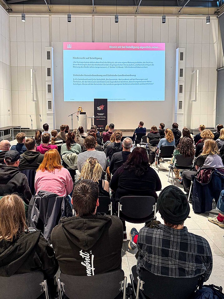 [Translate to Englisch:] großer Saal mit Zuhörern und Nadine Jukschat als Vortragende