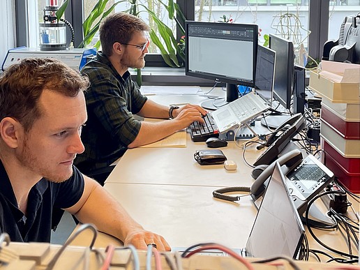 Jan-Hendrik Smith und Karl Jacobie sitzen an ihren Rechnern am Schreibtisch und arbeiten.