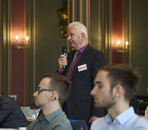 Prof. Haim steht am Sitzplatz und spricht in ein Mikrofon.