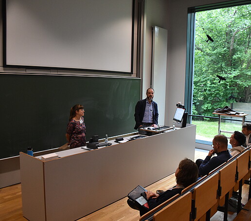 [Translate to Englisch:] 2 Redner stehen am Pult im Hörsaal