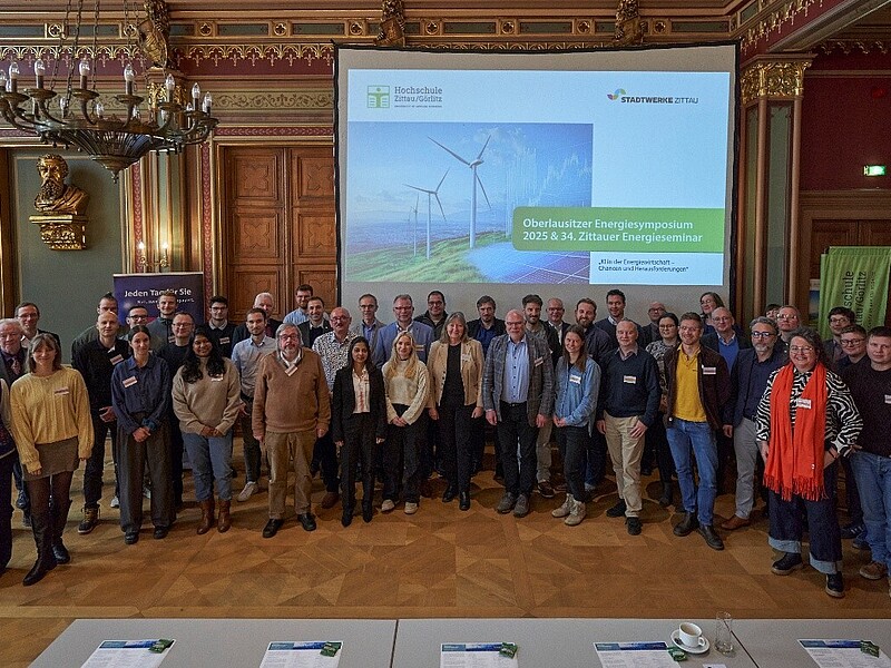 Im Bürgersaal des Zittauer Rathauses steht eine Gruppe Menschen nebeneinander und lächeln in die Kamera.