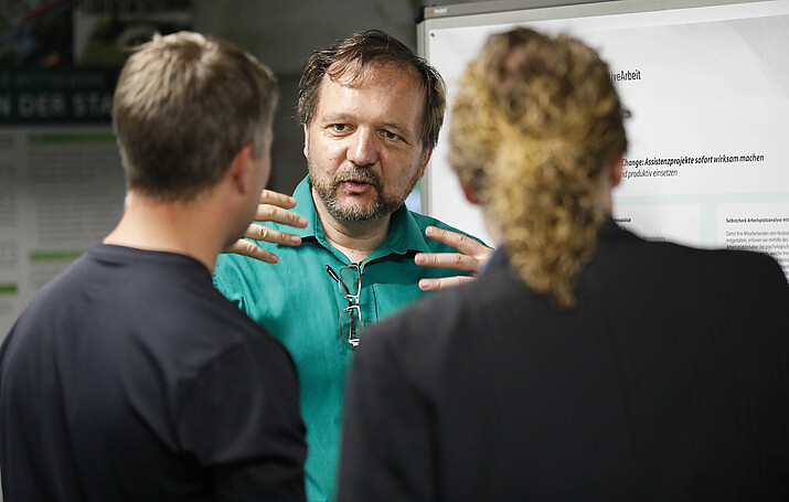[Translate to Englisch:] 2 Besucher im Gespräch mit David Sauer
